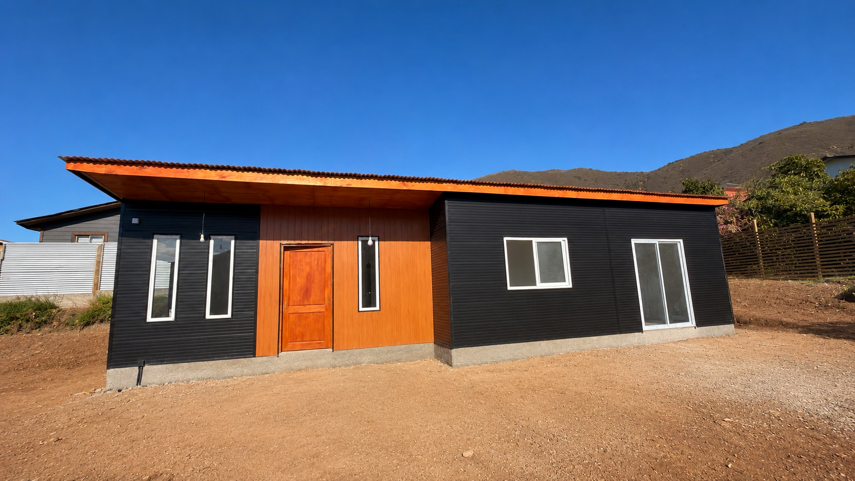 Casa Metalcon negra con revestimiento naranjo